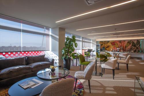 a living room with a couch and tables and chairs at Hotel Puerta America in Madrid