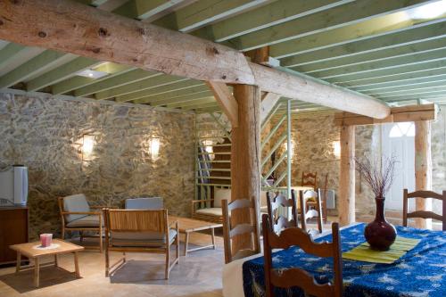 a room with a table and chairs and a stone wall at Chambres d'hôtes Les Gragniotes in Tournissan