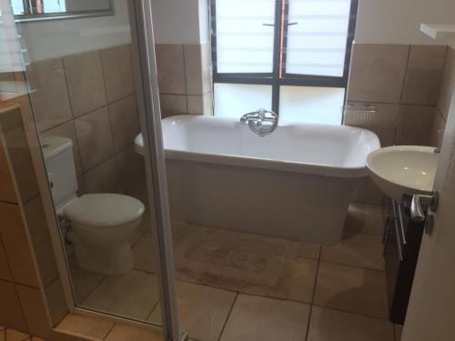 a bathroom with a tub and a toilet and a sink at Milkwood House in Wilderness