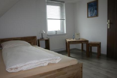a bedroom with a bed and a window and a table at Landgasthof am Bäumchen in Weißenfels