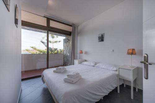 ein weißes Schlafzimmer mit einem Bett und einem Fenster in der Unterkunft Vista Dorada al mar balcón-Wifi By CanariasGetaway in Las Palmas de Gran Canaria