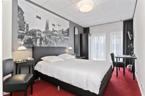 een slaapkamer met een groot wit bed, een bureau en een stoel bij Crown Inn in Eindhoven