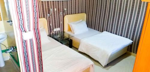 um pequeno quarto com 2 camas e uma janela em Divers home em Ras al-Khaimah
