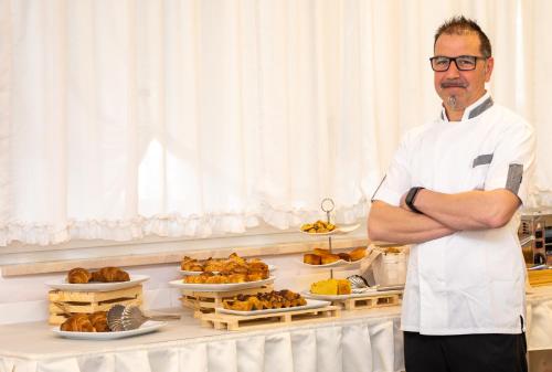 Un hombre de pie en una cocina con los brazos cruzados. en Hotel Venezuela, en Lido di Jesolo