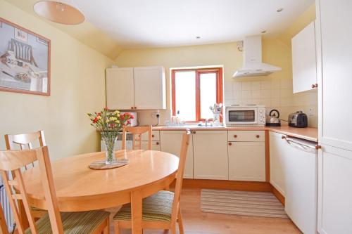 a kitchen with a wooden table and a table and chairs at Ferryman's Cottage in Glasbury