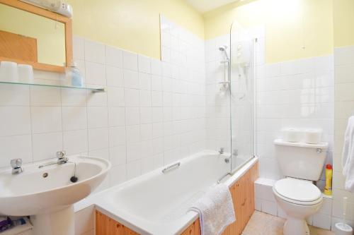 a bathroom with a sink and a toilet and a bath tub at Ferryman's Cottage in Glasbury