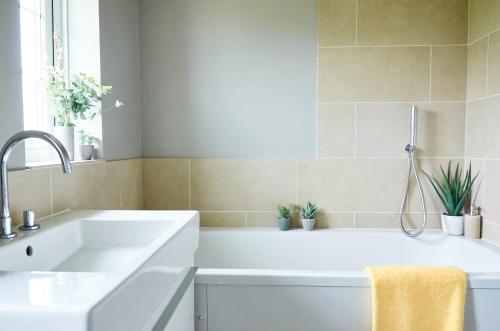 a white bathroom with a sink and a tub at Bell Lodge in Chichester