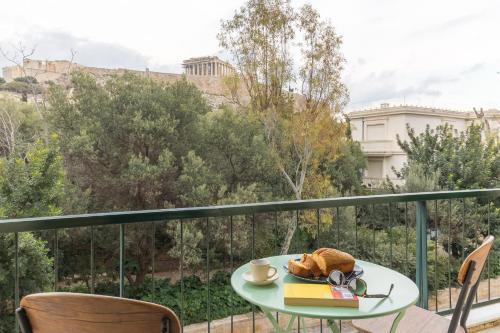 a table with a book and a cup of coffee on a balcony at Holodek Apartments : Parthenon in Athens