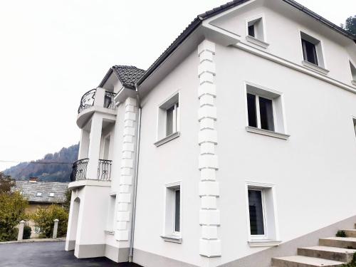a white building with a balcony at Villa Hillside Apartment in Jesenice