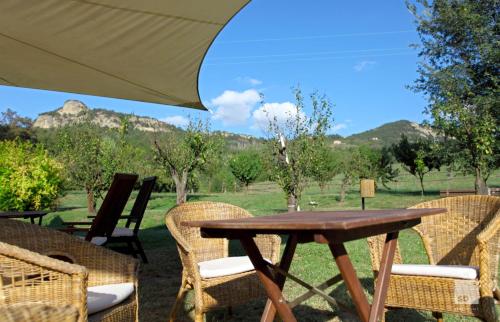 a wooden table with chairs and an umbrella at Locanda Dei Cinque Cerri in Sasso Marconi