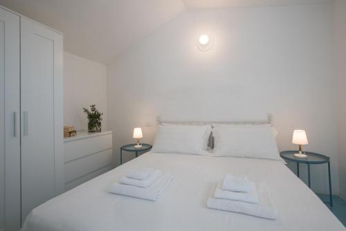 een wit bed met twee witte handdoeken erop bij Sul Mare Sardegna Villa Eunice in Villasimius