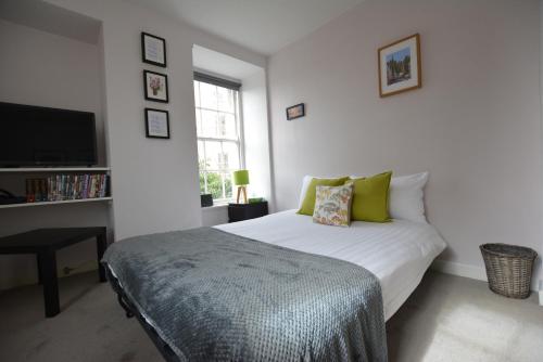 Schlafzimmer mit einem Bett mit grünen Kissen und einem TV in der Unterkunft The Bolthole - Fantastic Old Town Location! in Edinburgh