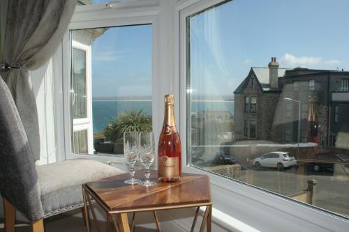 una botella de vino sentada en una mesa junto a una ventana en Rivendell Guest House en St Ives