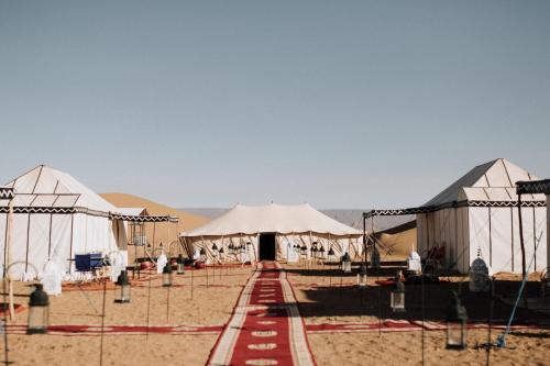Un groupe de tentes au milieu du désert dans l'établissement Desert Luxury Camp Erg Chigaga, à El Gouera
