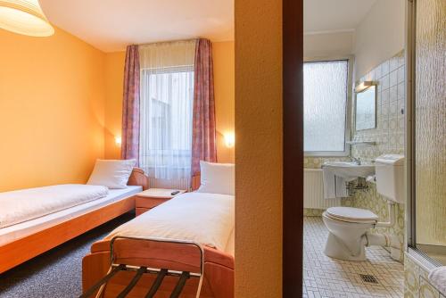 a hotel room with two beds and a bathroom at Hotel Carlton in Dortmund