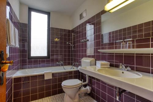 a bathroom with a toilet and a sink and a tub at Hotel Carlton in Dortmund