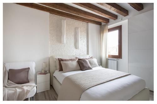 a white bedroom with a bed and a chair at Biennale Family Apartment in Venice in Venice