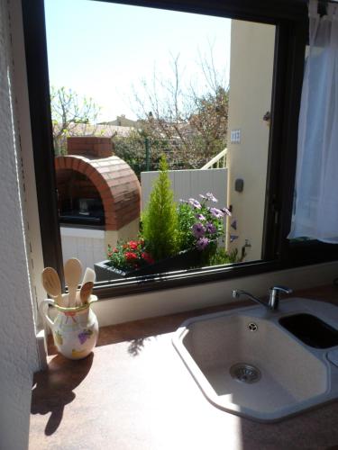 een keuken met een wastafel en een raam met bloemen bij La Pergola de la Plage in Gruissan