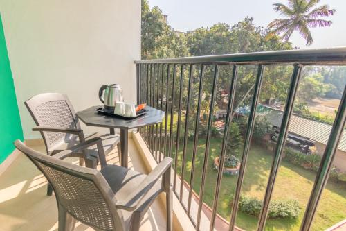 balcón con mesa y sillas y vistas a un patio en Aastha Escape Resort near Calangute Beach, en Calangute