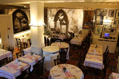 a restaurant with white tables and chairs in a room at La Mère Poulard in Le Mont Saint Michel