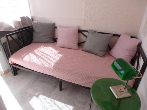 een klein bed met roze kussens en een groene tafel bij La Pergola de la Plage in Gruissan