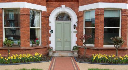 a brick building with a green door and flowers at Ravenhill House in Belfast