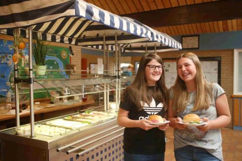 two girls standing in front of a food stand with plates of food at Jugendherberge Otterndorf in Otterndorf