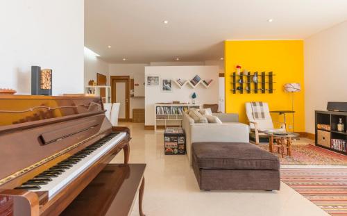 a living room with a piano and a yellow wall at Eco Apartment @ Torre Verde (Green Tower) in Lisbon