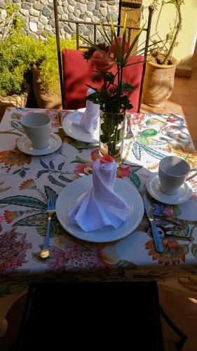 Una mesa con platos y tazas y un jarrón con una servilleta. en Riad Gallery 49 & Spa, en Marrakech