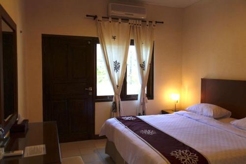 um quarto com uma cama grande e uma janela em Niramaya Villa em Seminyak
