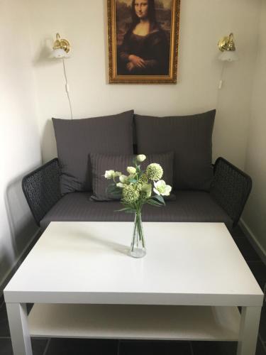 a white coffee table with a vase of flowers on it at Lolland Bed & Breakfast in Søllested