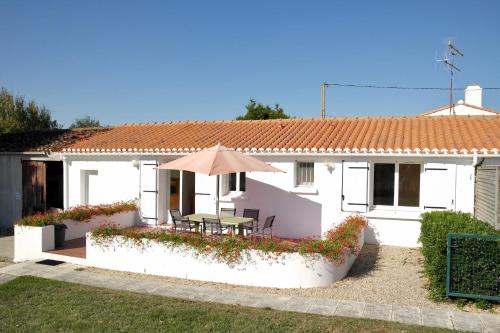 a white house with a table and an umbrella at Maison de campagne pour 6 in Commequiers