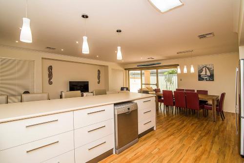 a kitchen with white cabinets and a table with chairs at Busselton Holiday Home in Busselton