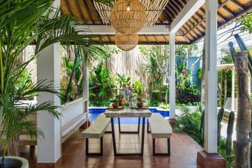 a patio with a table and benches and palm trees at Smiling Cactus Villas - Seminyak in Seminyak