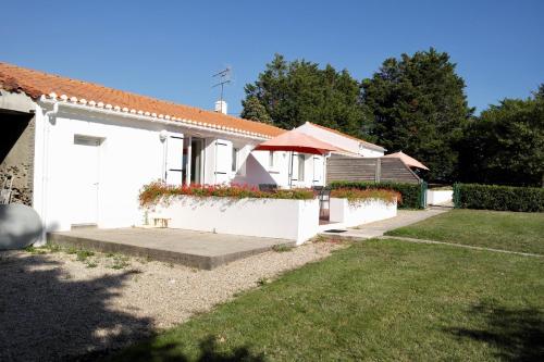 a white house with flowers on the side of it at Maison de campagne pour 6 in Commequiers