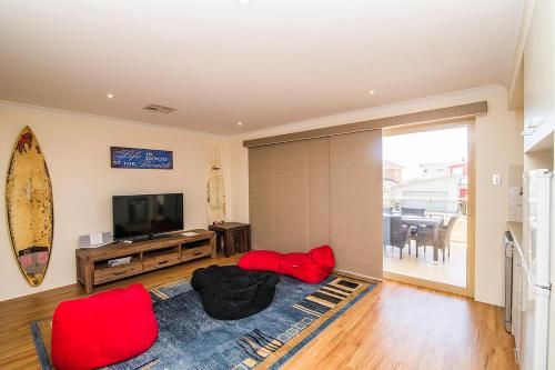 a living room with a television and a surfboard on the wall at Busselton Holiday Home in Busselton