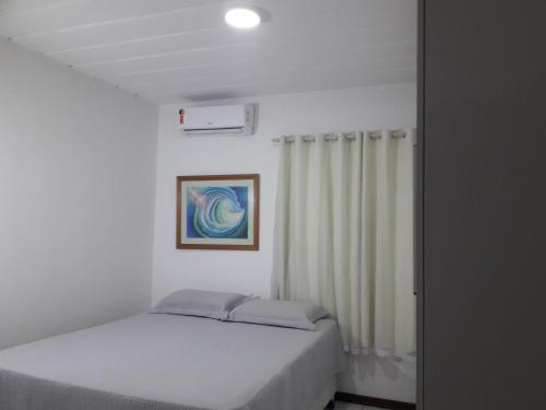 a white bedroom with a bed and a curtain at Apartamento Stela Maris Praia e Aeroporto in Salvador