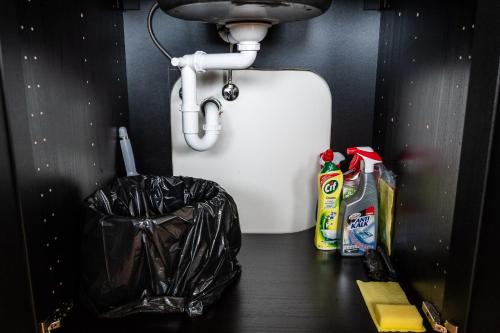 a bathroom with a sink and a trash can at Liepaja Apartments in Liepāja