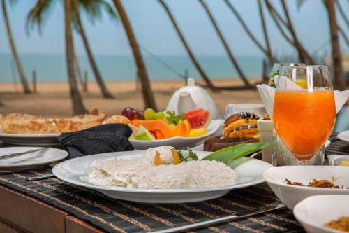 a table with plates of food and a glass of orange juice at Serendivi Resort Villa in Tangalle
