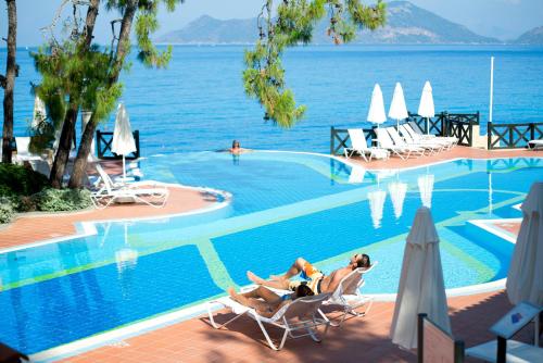 a swimming pool with two people laying in chairs by the water at Liberty Lykia in Oludeniz