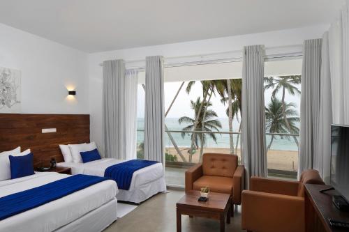 a hotel room with two beds and a view of the beach at Serendivi Resort Villa in Tangalle
