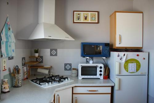 La cuisine est équipée d'un réfrigérateur blanc et d'un four micro-ondes. dans l'établissement Belle maison à 600 mètres de la grande plage de Saint-Gilles-Croix-de-Vie, à Saint-Gilles-Croix-de-Vie