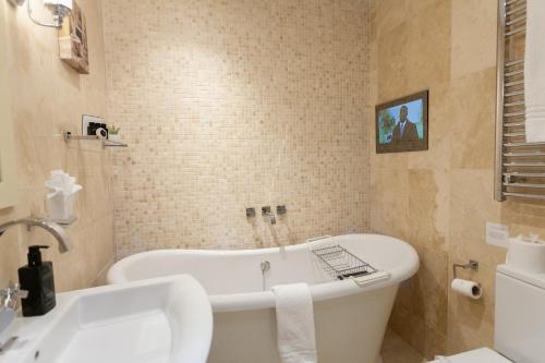 a bathroom with a bath tub and a sink at The Somerville in Torquay