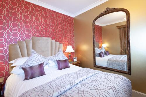 a bedroom with a large bed and a mirror at The Somerville in Torquay