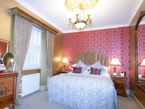 a bedroom with a bed and a chandelier at The Somerville in Torquay