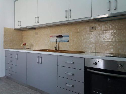 a kitchen with white cabinets and a sink at Sunset Guest house in Himare