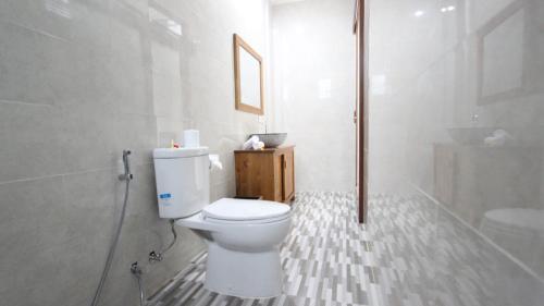 a white bathroom with a toilet and a shower at Pondok Serayu in Ubud