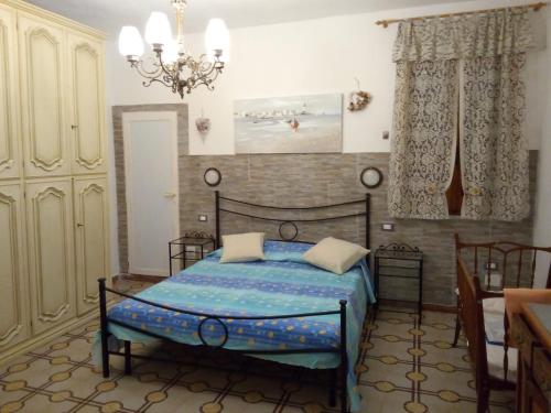 una camera con letto e lampadario a braccio di appartamento " Il Ginepro" a Carloforte