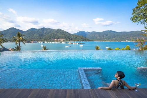 una joven sentada en una piscina con vistas a un lago en Bhuvarin Resort en Ko Chang