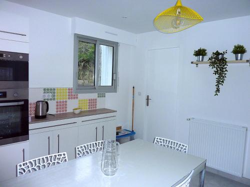 a white kitchen with a table and a yellow light at Un style balnéaire moderne pour profiter de la mer in Pornichet